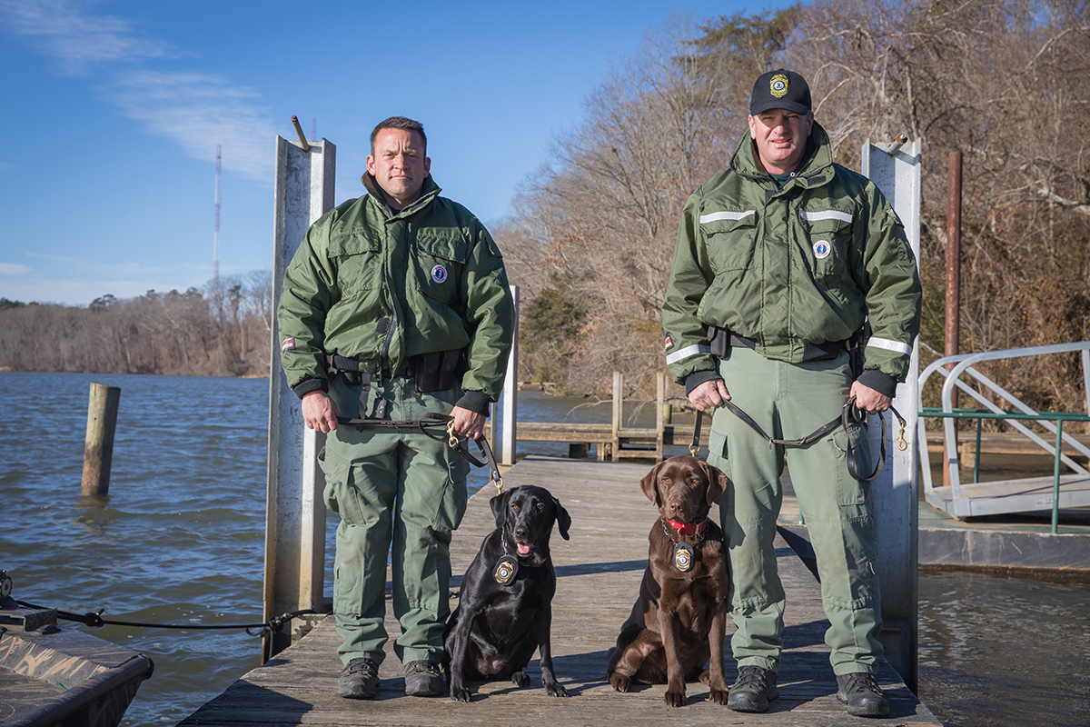 CPO James Patrillo 和 K 9 Bailey（左）以及高级 CPO Wes Billings 和 K 9 Molly 在码头上。