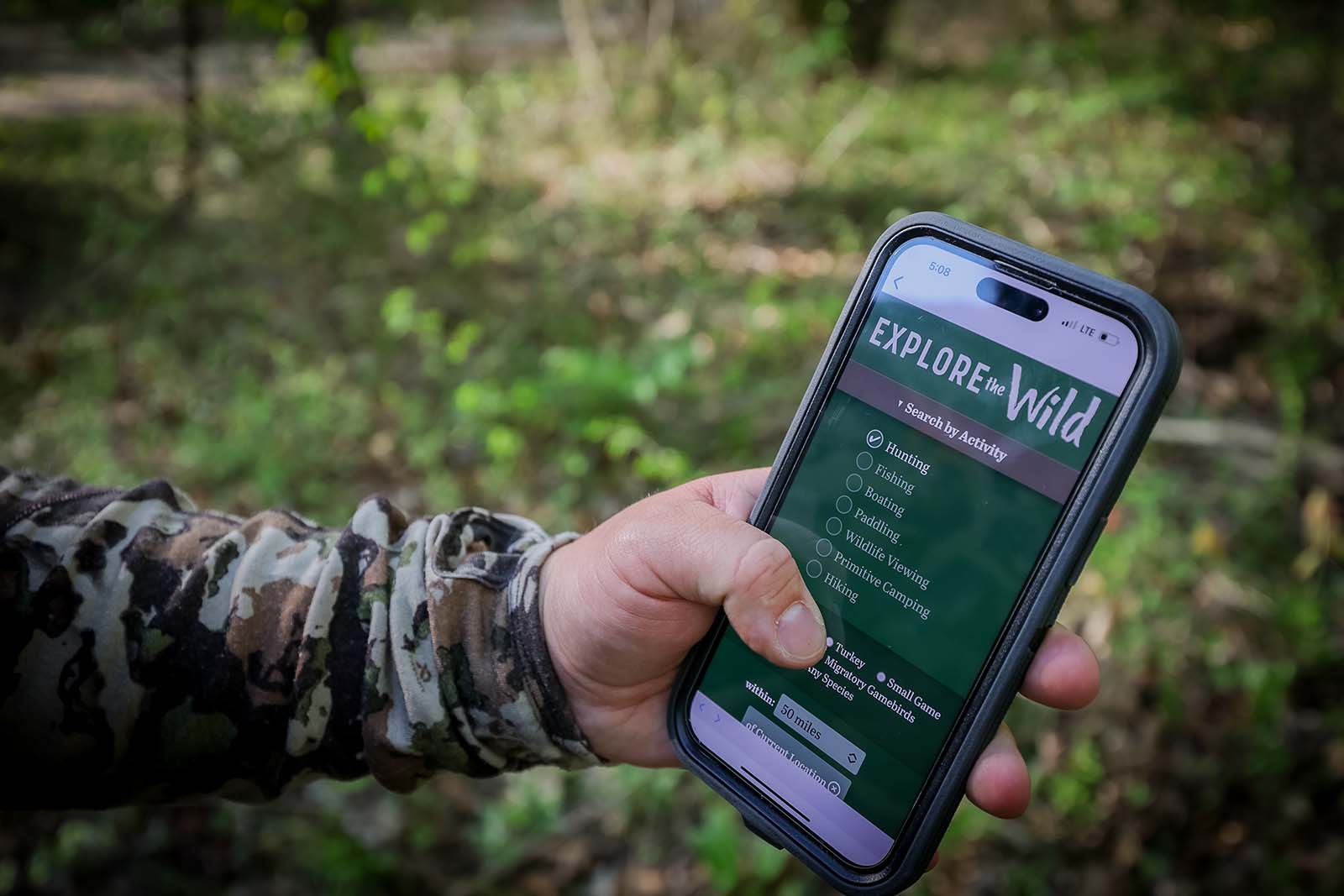 一只手拿着显示“探索荒野”的智能手机