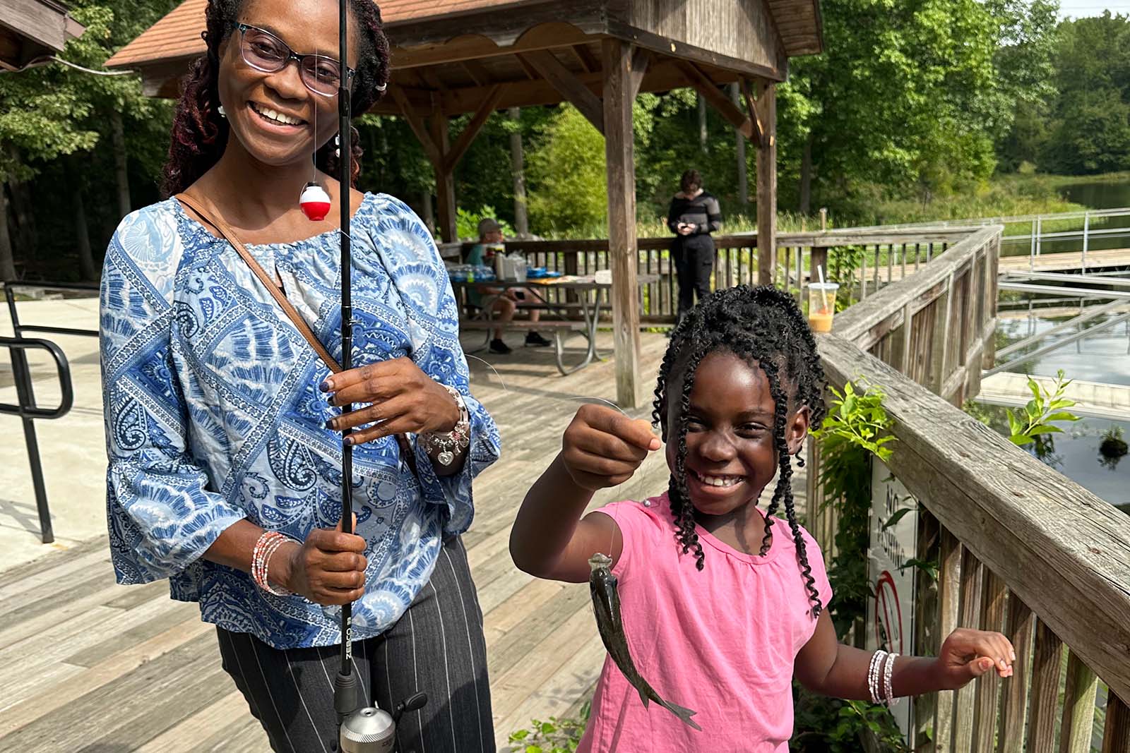 一名妇女和儿童拿着一根钓鱼竿和一条鱼