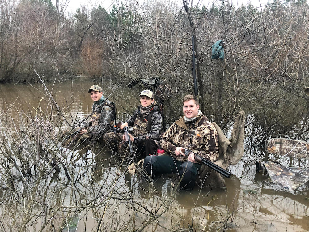一群男人坐在水中的一根木头上,这次他们没有找到鸭子
