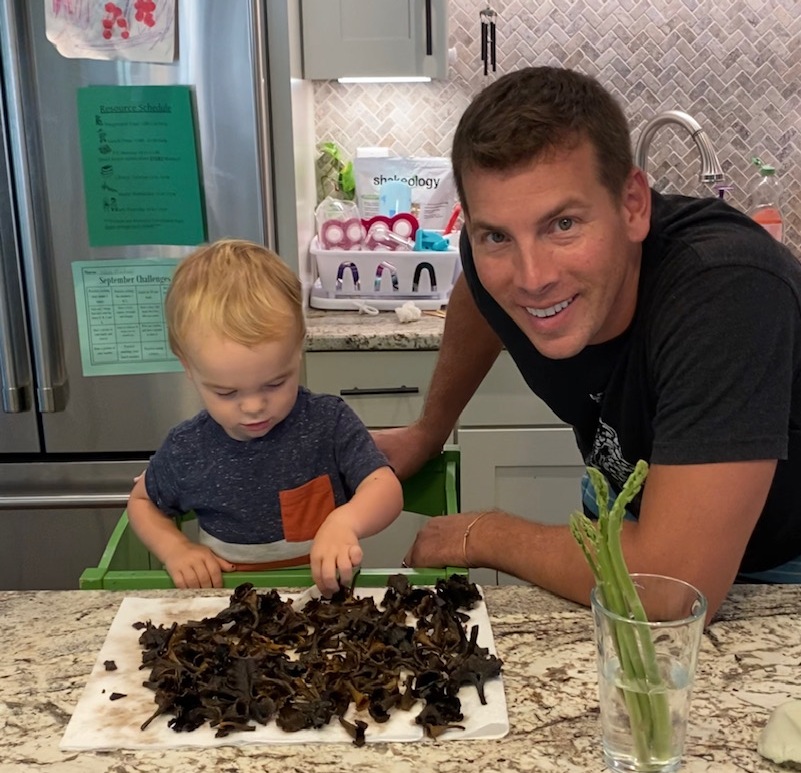 一个小男孩和他的父亲站在一堆蘑菇旁边的照片