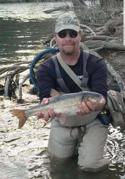 杰瑞·霍尔在湿地里抱着他所在州创纪录大小的秋鱼的照片