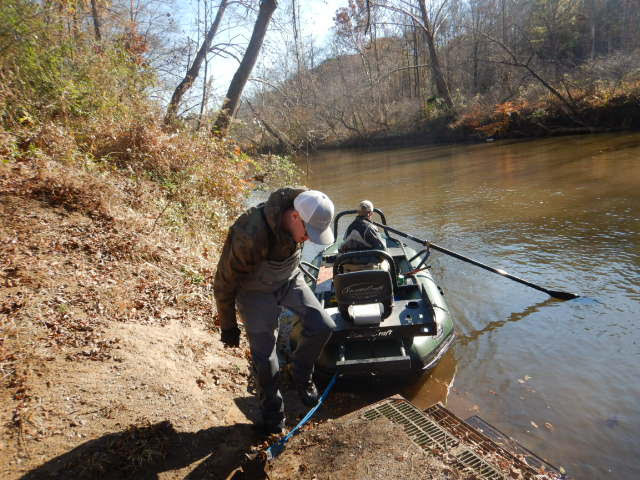绿色电捕鱼筏正与两名工作人员一起从陆地上移走