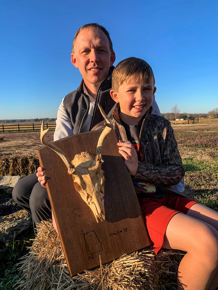 一名男子和他的太阳手持鹿头骨的照片,这是他们一起射杀的第一头鹿