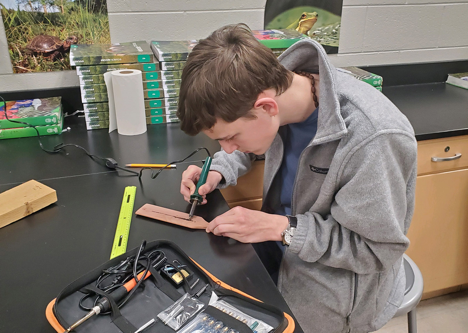 一张年轻男子在工作台上用火鸡叫桨上的烧木工具的照片。