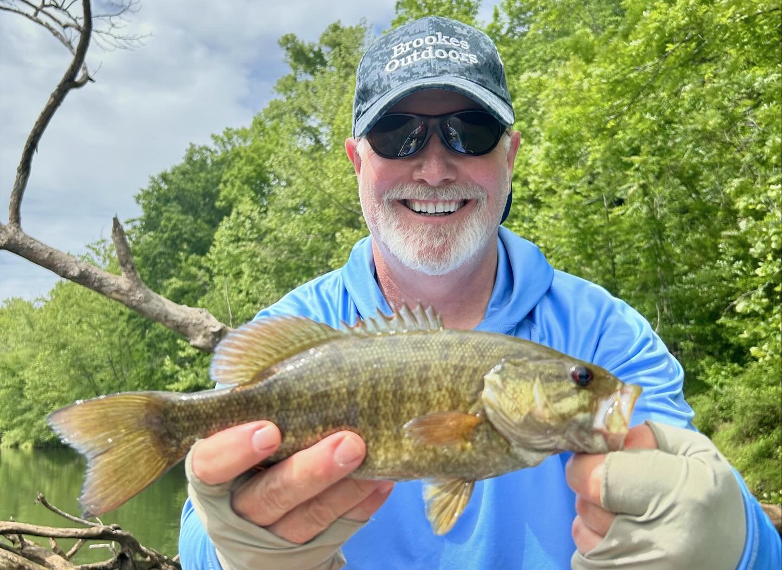 一名男子手持小嘴鲈鱼拍照。