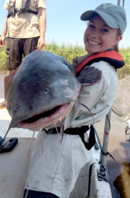 一个女孩抱着一条蓝色的大鲶鱼